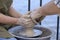 Teaching of wheel throwing. Potter hand correcting woman s ones during shaping clay blank on a potter& x27;s wheel