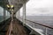 Teak lined Promenade Deck of modern cruise ship on a grey stormy