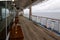 Teak lined Promenade Deck of modern cruise ship on a grey stormy day