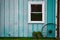 Teal barn with wagon wheel window and flower kettle planter hole in siding