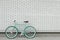 Teal bicycle next to white brick wall