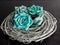 Teal blue paper roses on top of a gray wooden coiled wreath with a black slate background.  Simple and elegant home decor