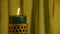 Teal candle trembling flame with yellow curtain background and blown out
