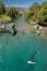 Teal green river water in Patagonia, Argentina with old bridge and girl swimming