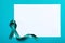 Teal ribbon and blank card on color background, top view