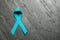 Teal ribbon on grey background, top view