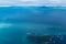 Teal waters of Alaska near Katmai National Park, with view of Augustine Island and the Aleutian Range of mountains. Aerial