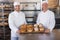 Team of bakers smiling at camera with trays of bread