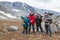 Team of Caucasian hikers with backpacks, four people standing in mountain valley, portrait with copyspace