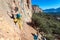 Team of Climbers Man and Woman ascending orange bright rocky Wall with rope and gear