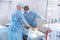 A team of doctors in the operating room conducts medical procedures. Surgeons in sterile clothing work in the hospital