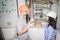 A team of electricians are talking near the electrical panel. A man and a woman in engineering helmets discuss the power supply of