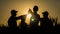 A team of energetic young people makes the high five mark in a picturesque wheat field at sunset.