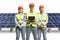 Team of engineers wearing reflective vests amd helmets at a solar farm