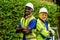 Team factory worker technician engineer men standing confidence with green working suite dress and safety helmet. Background of