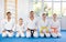 Team of family martial arts athletes is posing in gym with male coach.