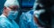 Team of medical doctors performs surgical operation in modern operating room using high-tech technology. Surgeons are