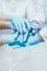 Team of medical workers in blue gloves holding hands together. Closeup