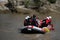 Team members rowing in the rafting boat down the murky river during summer time