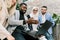 Team of multiethnical diverse business people, two men and two women, standing in modern office, discussing and working