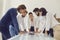 Team of office workers together with boss leaning over table studying documents and reports