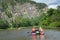 Team of people float down the River on inflatable catamaran among beautiful rocks and mountains of Russia, Bashkortostan