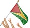 Team of peoples hands raising the Guyana national flag