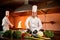 Ð team of professional chefs cook meals with frying pan and fire in the kitchen of restaurant.  Chief chef preparing dish using