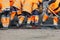 A team of road workers in orange reflective uniforms use shovels to scatter some of the asphalt to repair a section of the road on