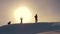 Team of travelers follow each other along snow ridge against backdrop of yellow sunset. coordinated teamwork of tourists