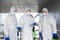 Team of virologists in hazmat suits making plan of disinfection