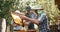 Team work of happy father beekeeper showing the honeycombs on the wooden frame full of bees to his two little sons