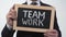 Team work written on blackboard in businessman hands, successful cooperation