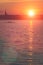 Team work of young men in a row boat silhouetted at sunset. Beautiful big sun light flares