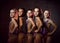 Team of young smiling girls gymnasts in purple shiny sport body posing over grey background