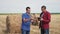 Teamwork agriculture smart farming concept. Two men farmers workers studying a haystack in a field on digital tablet