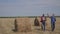 Teamwork agriculture smart farming concept. Two men farmers workers walking studying haystack in field on digital tablet