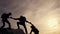 Teamwork of the business group. Male partners climb to the top. Silhouette of a helping hand at sunset. The concept of