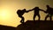 Teamwork of business people. Climbers silhouettes stretch their hands to each other, climbing to the top of hill