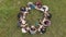 Teamwork concept. A group of high school students sit on the grass in a circle. Drone view.