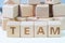 Teamwork concept, wooden cube block with letters forming word TEAM on white gridline notebook, power of working together to get