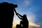 Teamwork couple helping hand trust assistance silhouette in mountains, sunset.