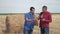 Teamwork lifestyle agriculture smart farming concept. two men farmers workers studying a haystack in a field on digital