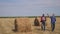 Teamwork lifestyle agriculture smart farming concept. two men farmers workers walking studying a haystack in field on