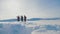 Teamwork. men tourists climbing walking top mountains rocks peak group team sunlight silhouette on snow feet winter snow