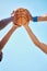 Teamwork, sports and hands on basketball ball with blue sky background in outdoor basketball court. Support, community