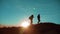 Teamwork. Two hikers enjoying sunrise from top of a mountain and dog. Two hikers with backpacks climbing a peak on cloud