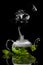 Teapot with brewed mint tea on a black background with rising steam