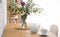 Teapot, cup and flowers on wooden dining table. Kitchen interior