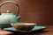 Teapot and cup of freshly brewed tea on wooden table, closeup. Traditional ceremony